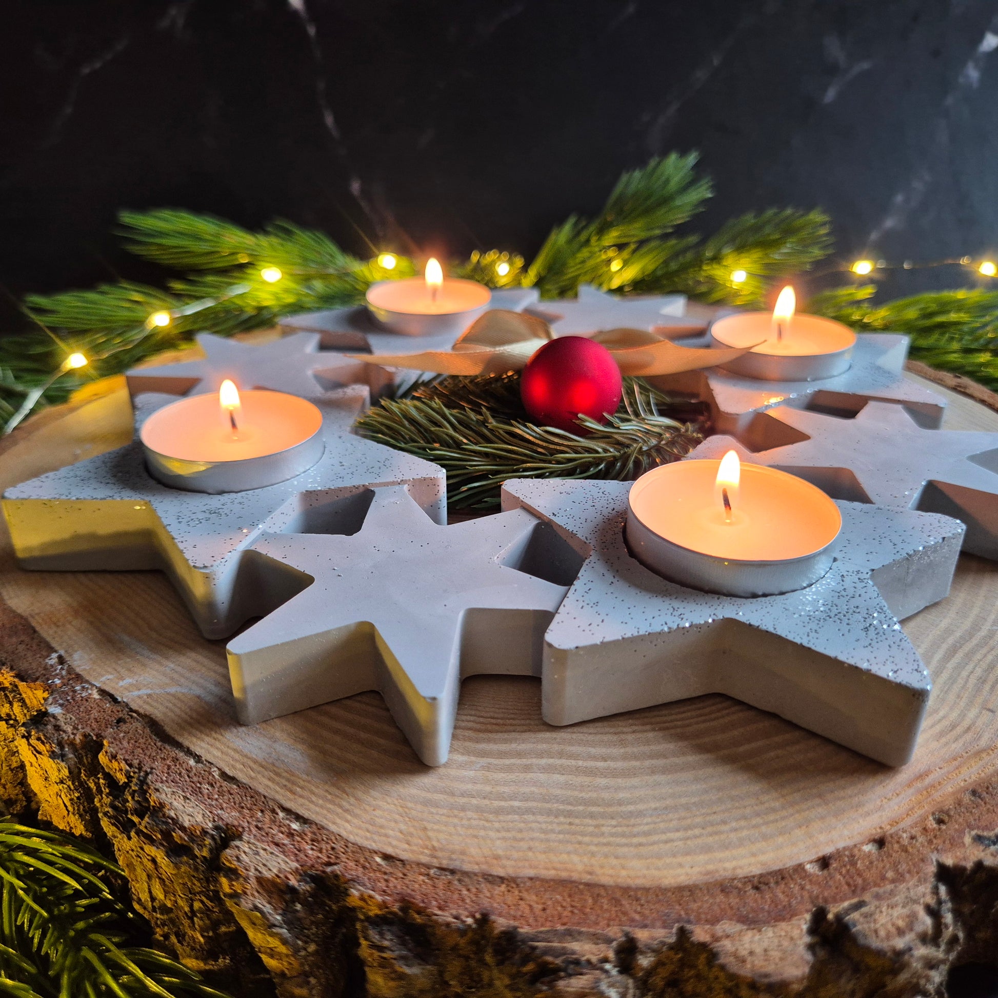 Adventskranz aus Sternen auf rustikaler Baumscheibe