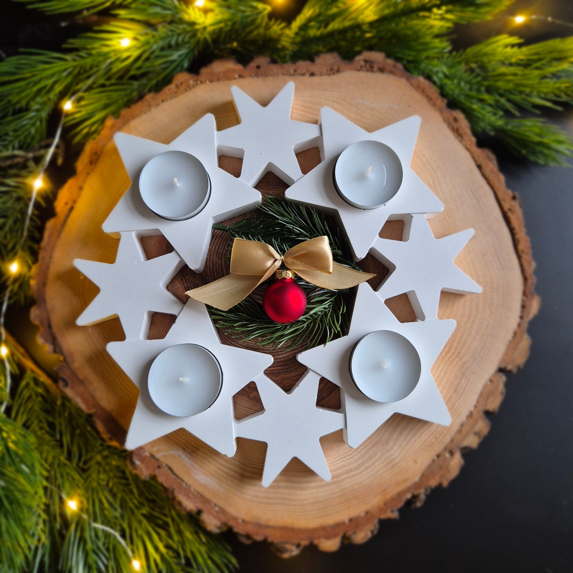 Sicht von oben auf acht im Kreis liegende Sterne mit vier Teelichter als Adventskranz