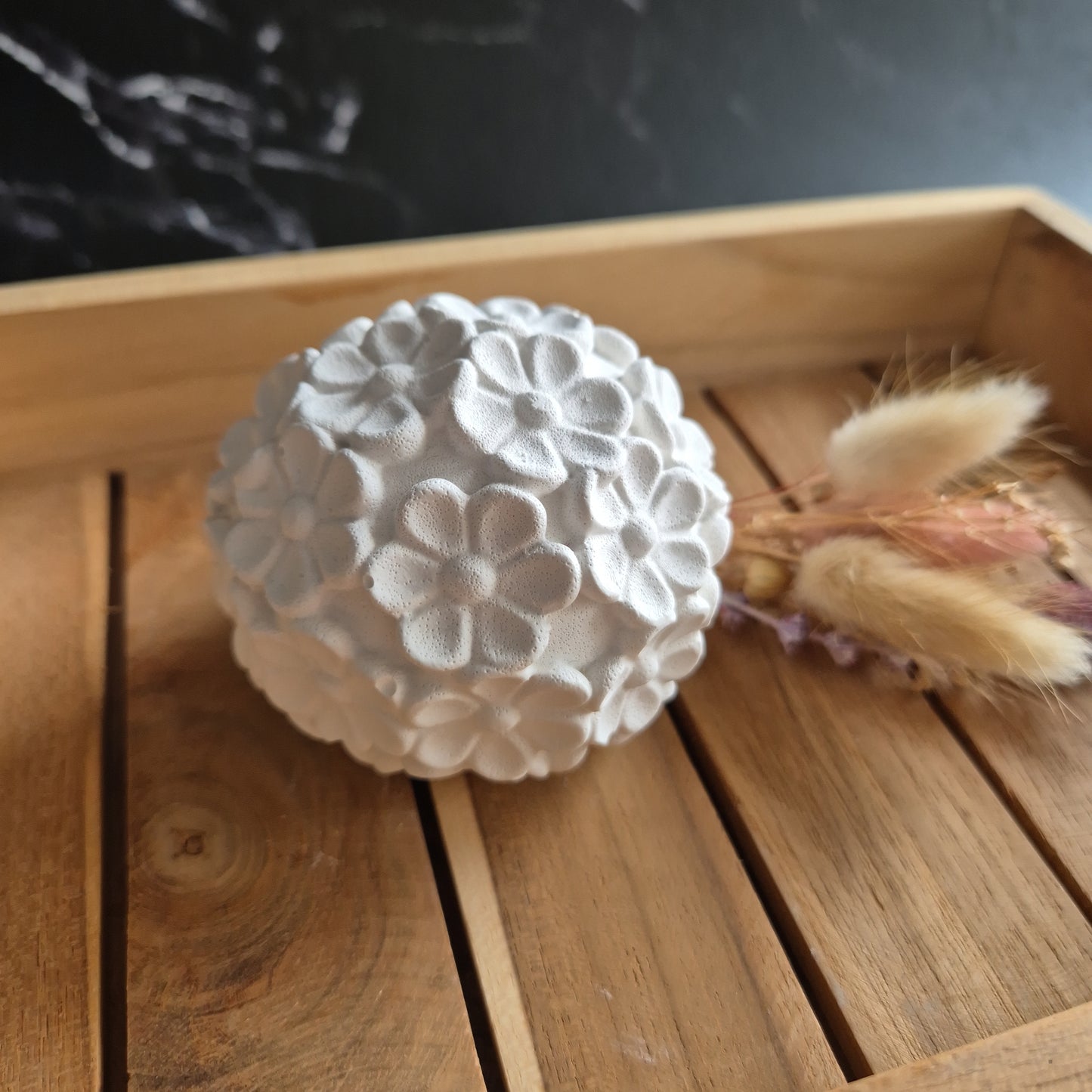 Nahaufnahme von einer weißen Kugel mit Blütenformen auf der Oberfläche 