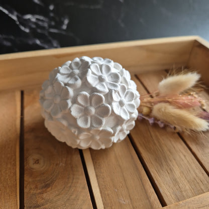 Nahaufnahme von einer weißen Kugel mit Blütenformen auf der Oberfläche 