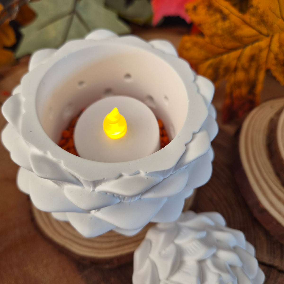 Tannenzapfen aus weißer Gießkeramik mit LED-Teelicht und Lichtlöchern